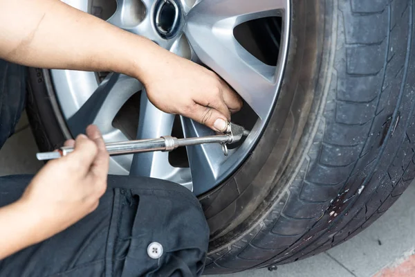 Mechanic checking tire pressure with tyre pressure gauge
