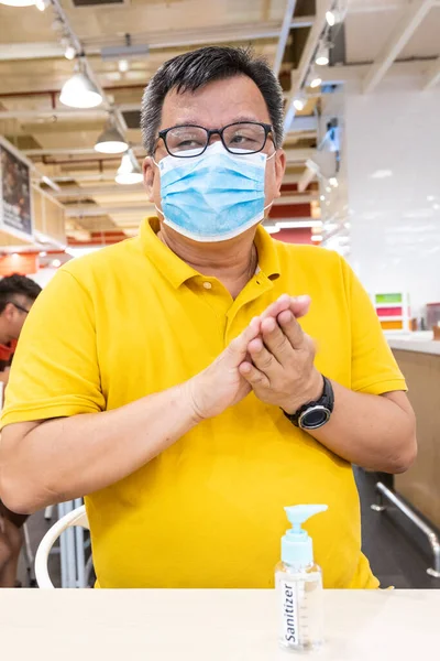 Asiatique homme avec masque facial appliquer désinfectant désinfectant désinfectant sur la main — Photo