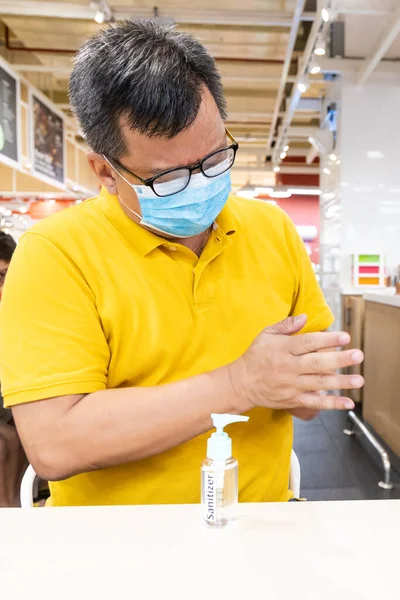 Asiatique homme avec masque facial appliquer désinfectant désinfectant désinfectant sur la main — Photo