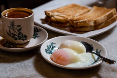 Yarısı haşlanmış organik yumurta, kahveli tost ekmeği, Malezya kopitiam 'da popüler Çin usulü kahvaltı. Düşük tuşlu ışıklandırma.
