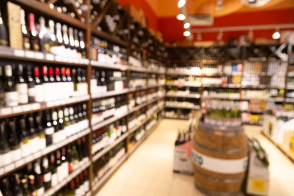 Blurred wine section of retailer with bottles on shelf racks as background in graphic pursuit