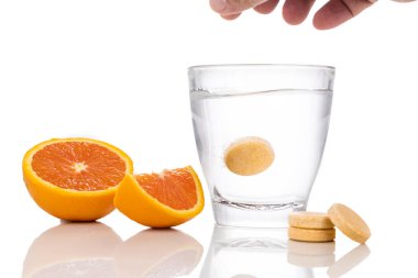 Portakal aromalı C vitamini tableti serileri beyaz arkaplanda bir bardak suda eriyip gidiyor.