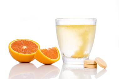 Portakal aromalı C vitamini tableti serileri beyaz arkaplanda bir bardak suda eriyip gidiyor.