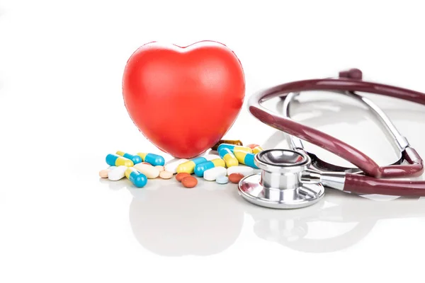 薬の丸薬 カプレット タブレット カプセルと赤の心臓 白い背景に小道具として聴診器と医療の概念 — ストック写真