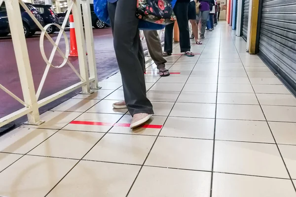 Social distancing being practiced where people are separated by a gap of at least 1 meter in queue into supermarket in Malaysia
