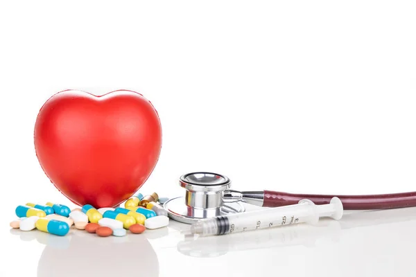 薬の丸薬 カプレット タブレット カプセルと赤の心臓 聴診器 白い背景の小道具として注射器と医療の概念 — ストック写真