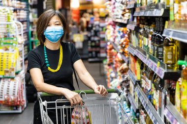 Malezya 'da yeni ihtiyaç olarak koruyucu yüz maskesi takan Asyalı kadın süpermarketten alışveriş yapıyor.