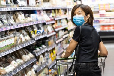 Malezya 'da yeni ihtiyaç olarak koruyucu yüz maskesi takan Asyalı kadın süpermarketten alışveriş yapıyor.