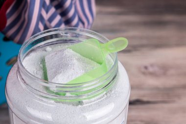 Ahşap yüzey üzerinde çamaşır tozu deterjanı bulunan kepçenin genel görünümü.