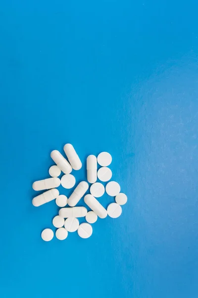Білі таблетки на синьому фоні — стокове фото