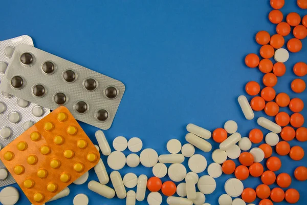 Різні таблетки на синьому фоні — стокове фото