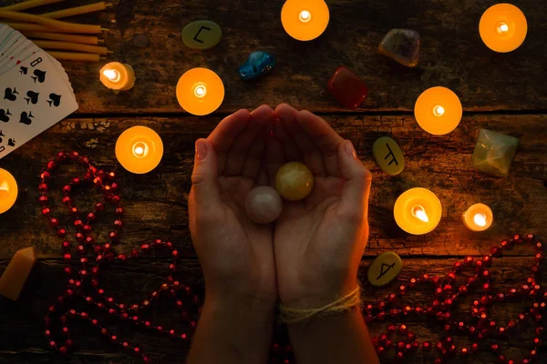 Fortuneteller holds crystal balls for divination against a background of candles and runes — Stock Photo, Image