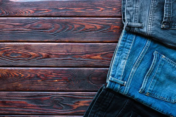 Jeans i olika färger på en trä bakgrund och utrymme för text — Stockfoto