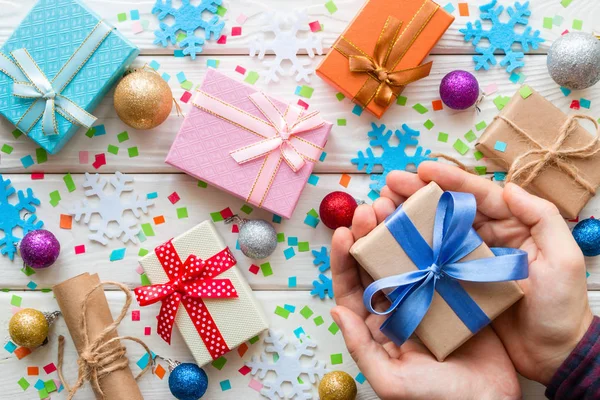Man håller en presentförpackning på bakgrunden av juldekorationer — Stockfoto
