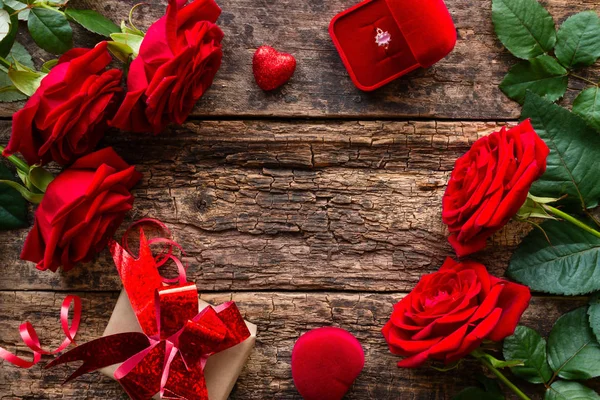 框架的红玫瑰, 礼物和一个结婚戒指在木背景 — 图库照片