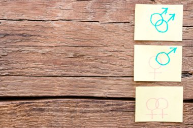 El kağıt metin yazabileceğiniz bir ahşap arka plan üzerinde cinsiyet sembolleri çizilmiş