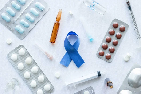 Cinta azul símbolo del cáncer de próstata y una variedad de medicamentos sobre un fondo blanco — Foto de Stock