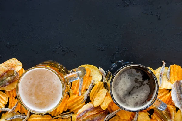 Zwei Becher Bier, Chips und Fisch auf schwarzem Hintergrund mit Platz für Text — Stockfoto