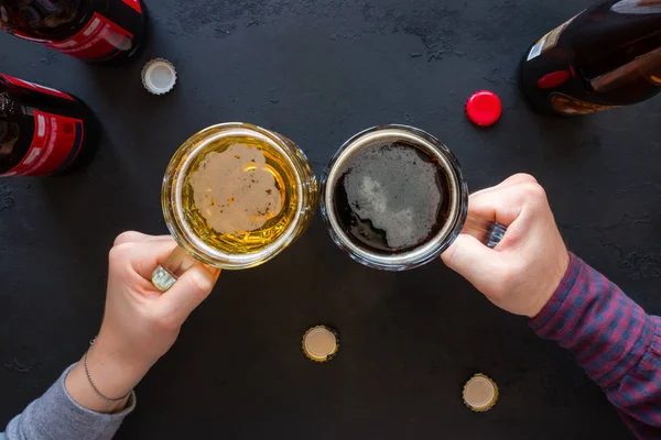 Gente sosteniendo tazas con cerveza sobre un fondo negro — Foto de Stock