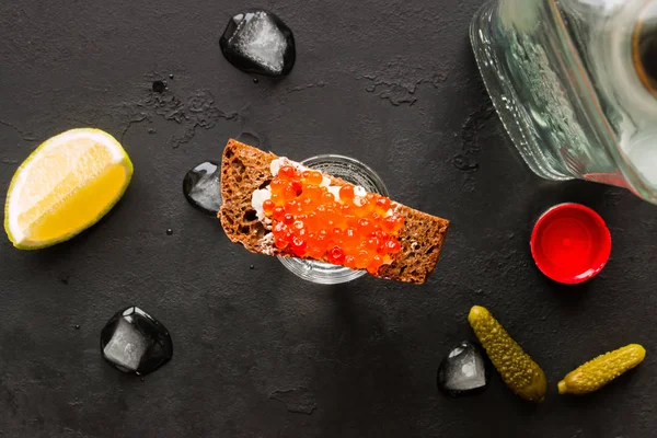 Постріл з горілки і різноманітні закуски на чорному тлі — стокове фото
