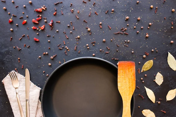 Empty frying pan and cutlery on a black background with space for text — Stock Photo, Image