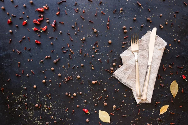 Cutlery and spices on a black background — Stock Photo, Image
