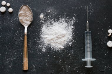 Beyaz toz, kaşık ve şırınga siyah bir zemin üzerine