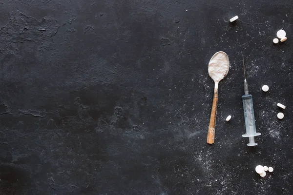 Compresse, cucchiaio con farmaci e una siringa su uno sfondo nero wi — Foto Stock