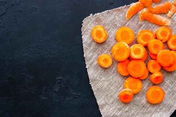 Sliced carrots on a napkin and place for text on a black background — Stock Photo, Image