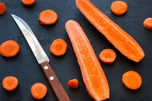 Kitchen knife and carrots on a black background — Stock Photo, Image