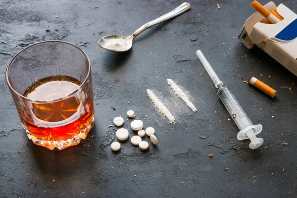 Alkohol im Glas, Drogen, Spritze, Zigarettenschachtel auf schwarzem Hintergrund. Konzept der schlechten Gewohnheiten — Stockfoto