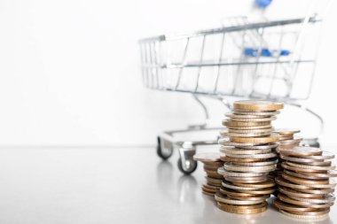Metin kavramı enflasyon ve yoksulluk için yeri olan beyaz bir zemin üzerinde bozuk para ve market arabası yığını