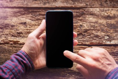 Adamın elinde boş siyah ekranlı bir cep telefonu var. Akıllı telefon ekran mesajlarını okur. ahşap arkaplan modelinde