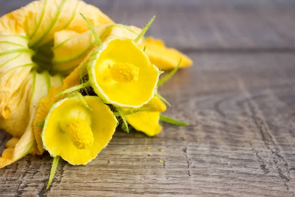 Flores amarelas de abobrinha em uma mesa de madeira — Fotografia de Stock