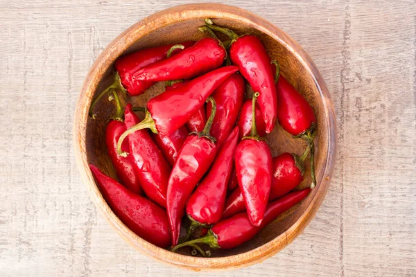 Sommige rode pittige chilipepertjes op houten tafel — Stockfoto