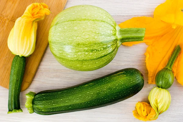 Green zucchini and blossoms on wooden table — Stock Photo, Image
