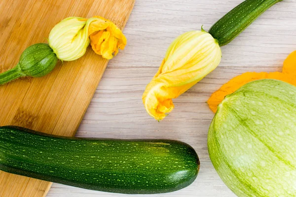 Green zucchini and blossoms on wooden table — Stock Photo, Image