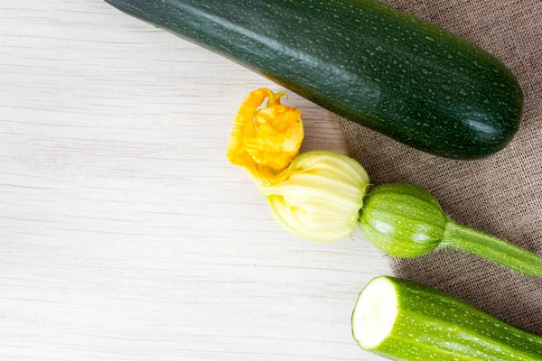 Grüne Zucchini und Blüten auf Holztisch — Stockfoto