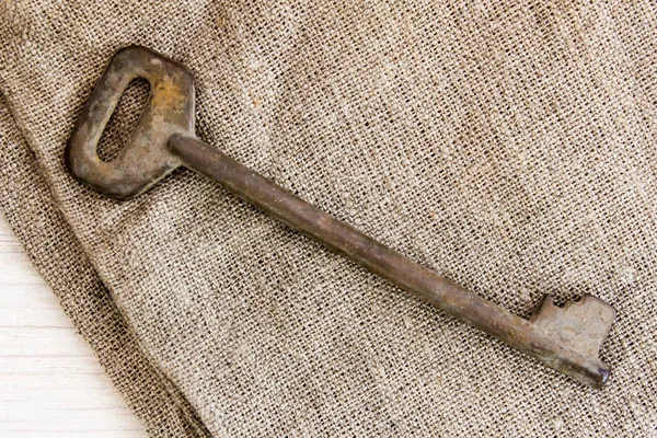 Old key on burlap on the table — Stock Photo, Image