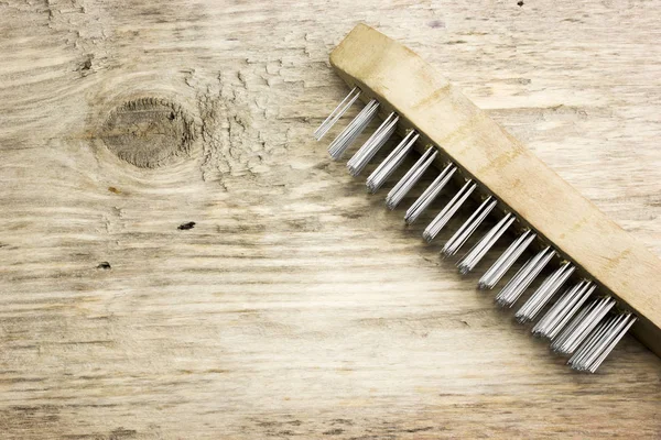 Brush with steel bristles on a wooden table — Stock Photo, Image