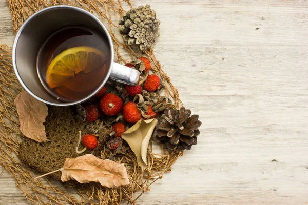 Tee mit Beeren von Wildrose in einer Metallschale auf einem Holztisch — Stockfoto
