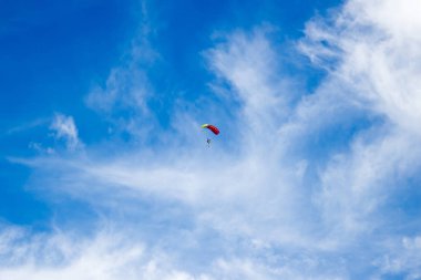 Mavi gökyüzünde bulutlar ile yalnız bir paraşütçü