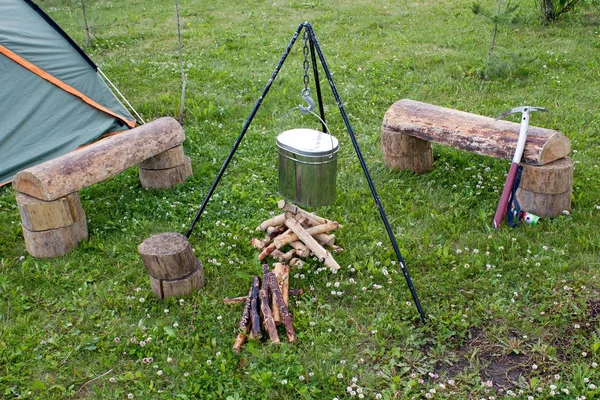 Campamento turístico, tienda de campaña, leña y una olla en la hierba verde — Foto de Stock