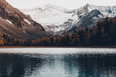 Bulutlu yağışlı hava kayalarda yansıtılmış yüzeyde yansıması ile dağ gölü. Dağ ülke ve doğa güzelliği.