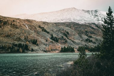 Bulutlu yağışlı hava kayalarda yansıtılmış yüzeyde yansıması ile dağ gölü. Dağ ülke ve doğa güzelliği.