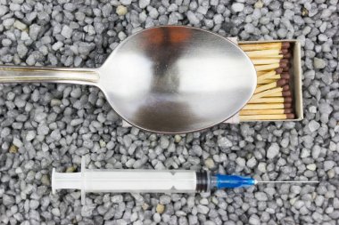 Plastik şırınga, bir kaşık ve bir maç iyi çakıl. Tıp, tıp. Uyuşturucu almaya.