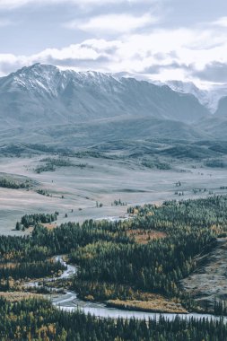 Bulutların altında güzel dağ silsilesi. Kayalar karlı dorukları. Altay Cumhuriyeti'dağ vadinin görünümü.