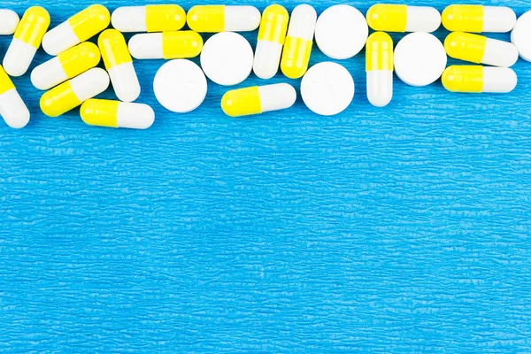 白色和黄色药丸在蓝色背景 医疗保健药品 — 图库照片
