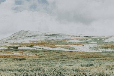 Bulutlu gökyüzü renkli yumuşak tepelerde.