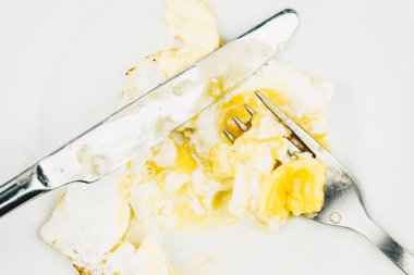 Plaka yiyecek kalıntıları. Çatal ve bıçak bir beyaz plaka ile pişmiş yumurta, öğle yemeği restoranda.